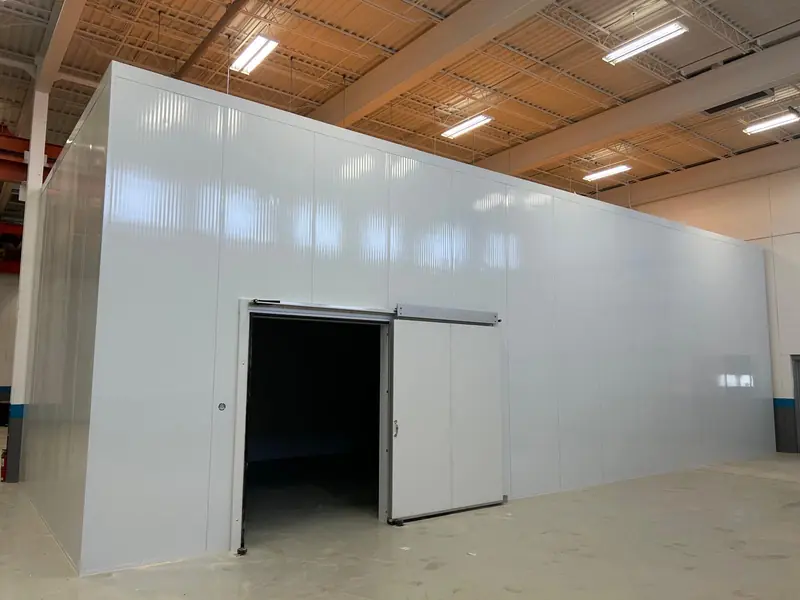 Large insulated metal panel cold room with a sliding door inside a warehouse