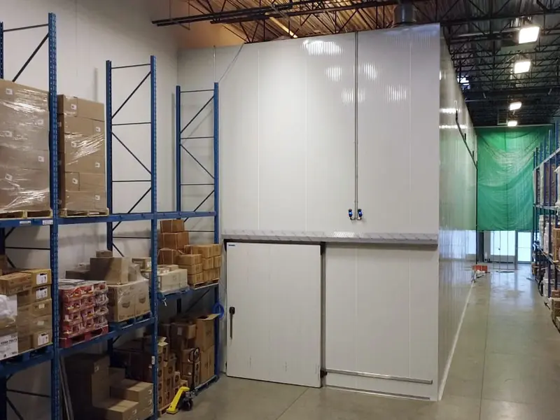 Two-storey insulated panel cold room beside pallet racking in a distribution warehouse