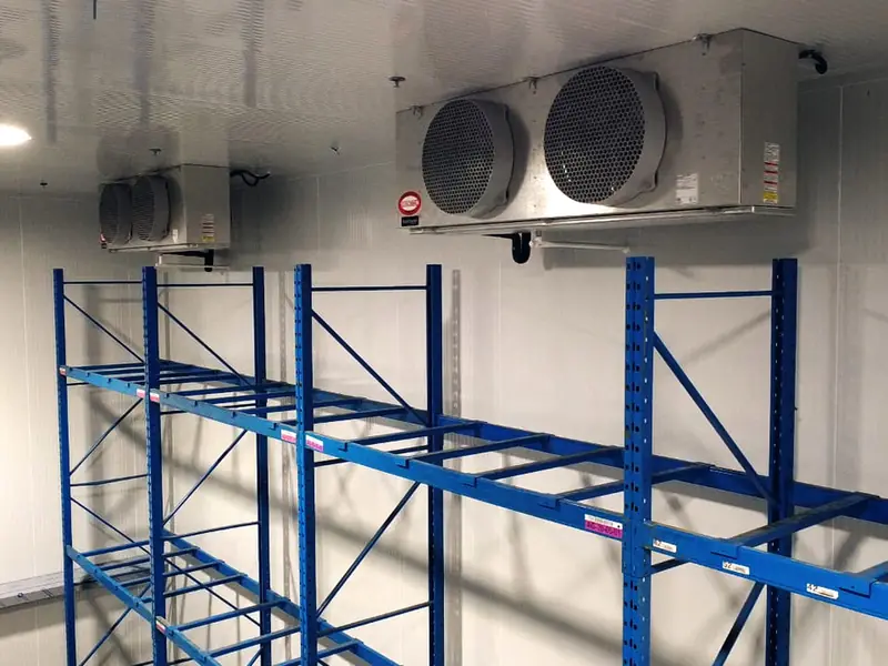 Ceiling-mounted evaporators above blue pallet racking in an insulated cold room